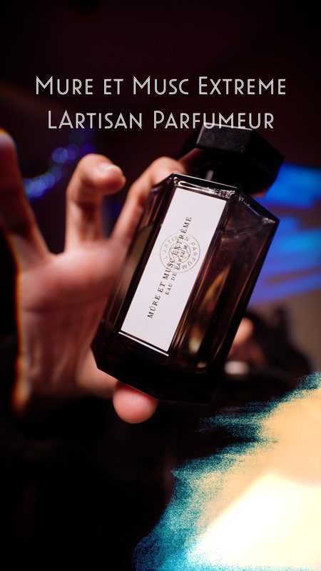 L'Artisan Parfumeur Mûre et Musc Extrême bottle caught mid-reach in teal and orange light — fragrance still