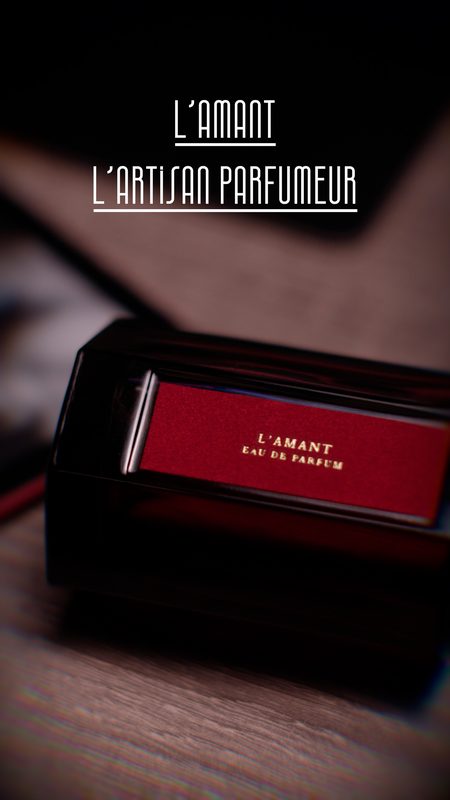 L'Artisan Parfumeur L'Amant bottle with red label in low, warm light — fragrance product photography